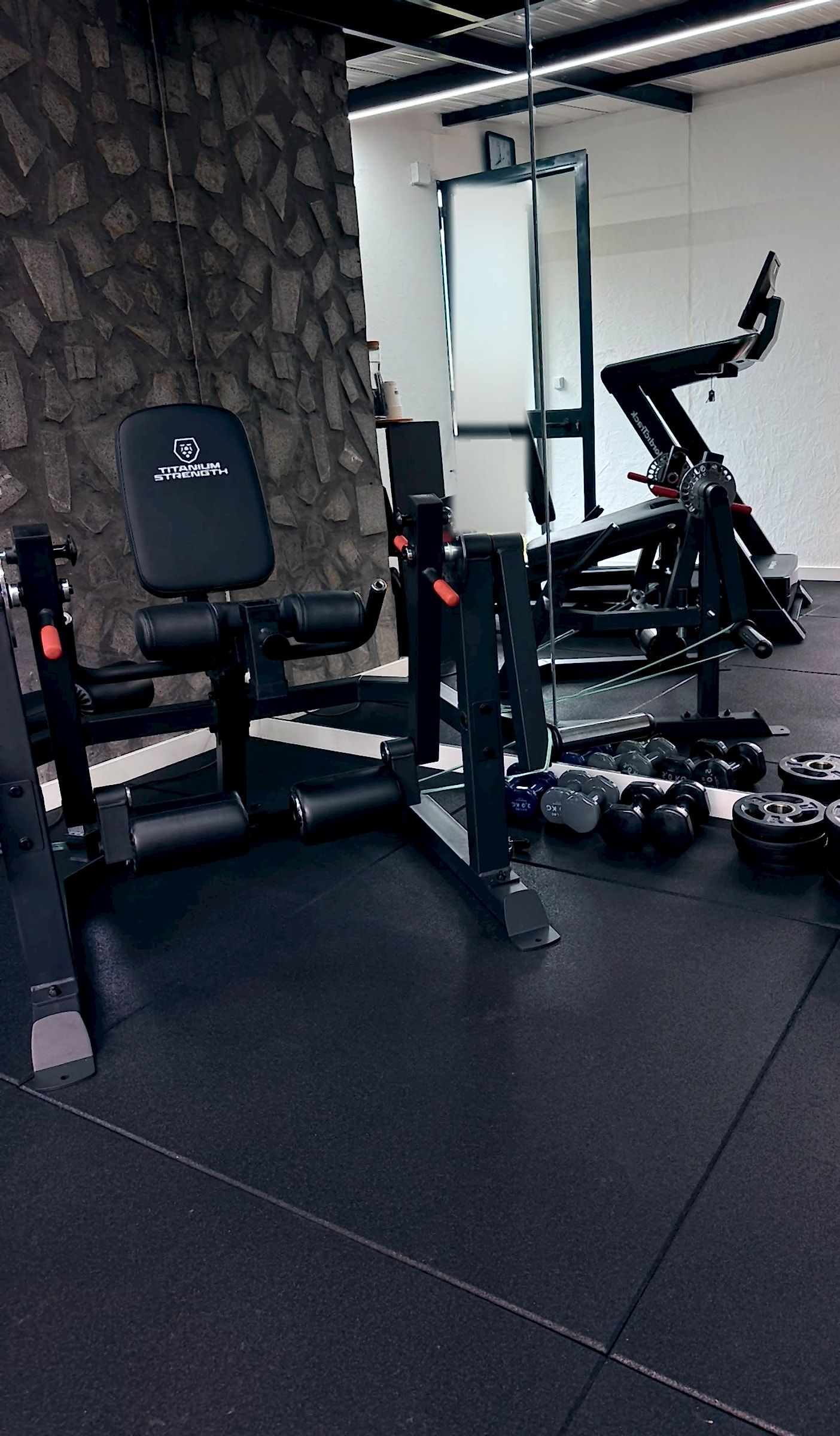 Espaço de treino privado: máquina de extensão de pernas junto ao pilar de pedra